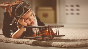 Bambino sognatore vestito da aviatore con modellino aeroplano